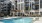 Sunny pool deck at The Shipwright apartments in Lynn, MA with lounge chairs, shaded seating, and modern apartment exterior in the background